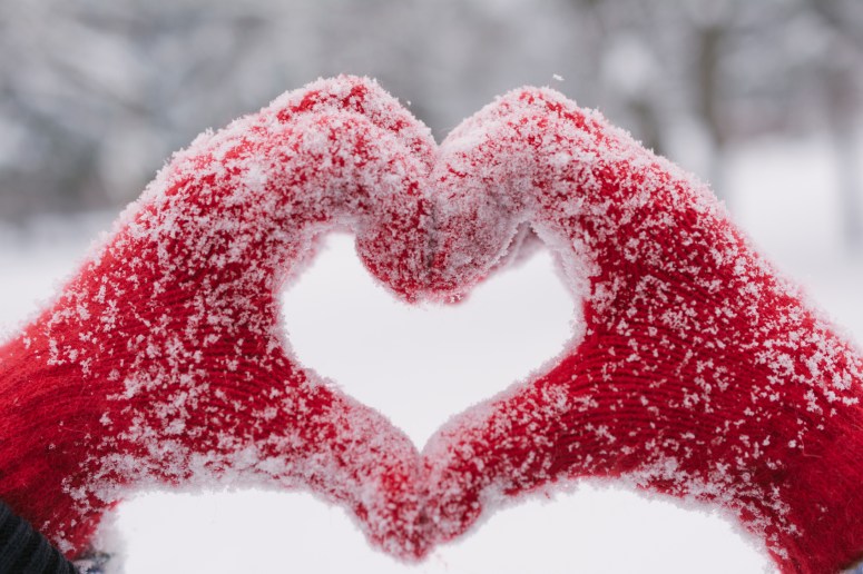 Woman making heart symbol with snowy hands